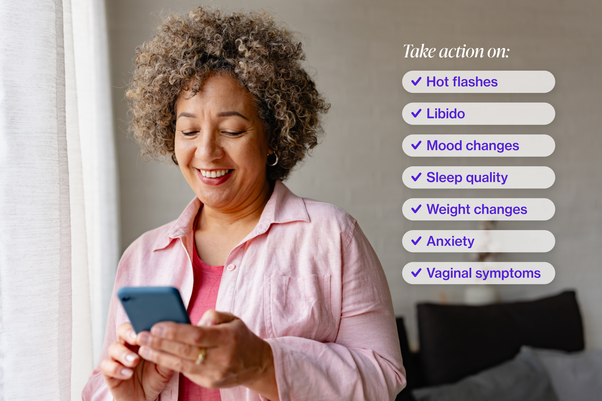 Woman with short curly hair looking at her iphone and smiling