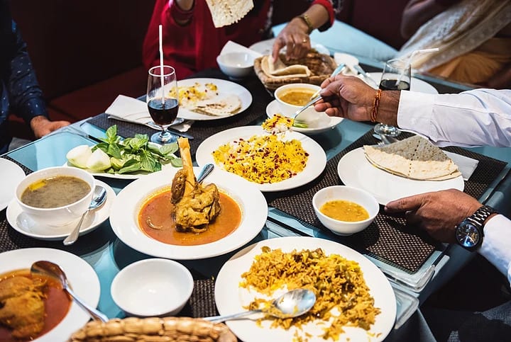 Table with various foods and people sitting around it