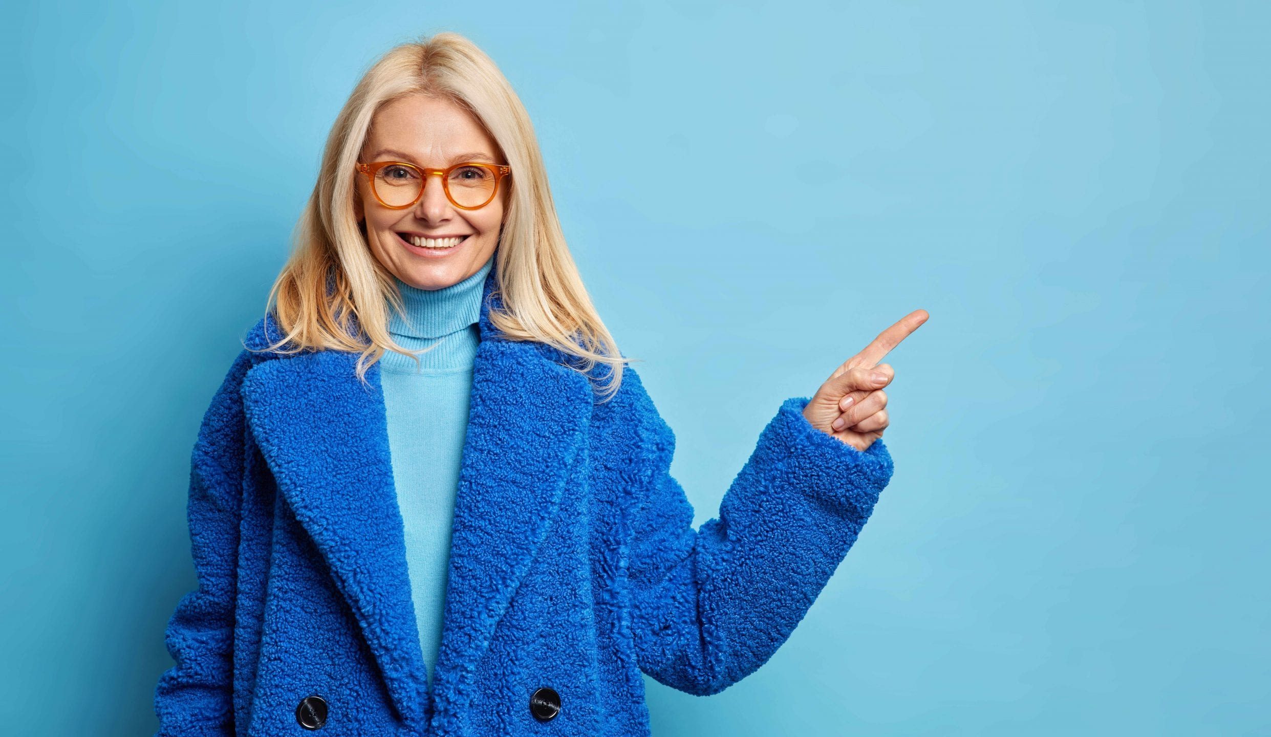 A smiling blonde woman in a blue coat