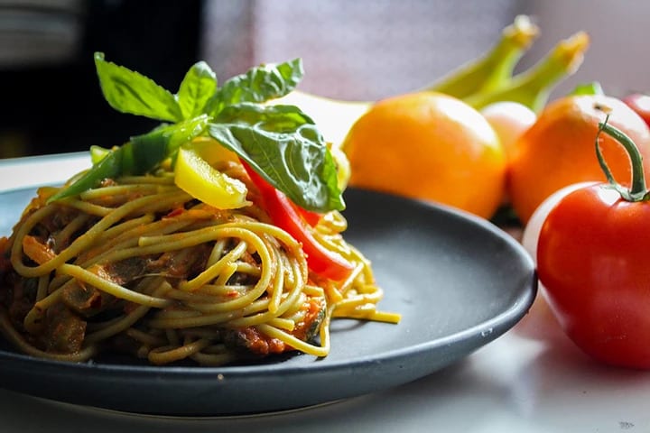 A photo of a pasta plate with tomatoes around it