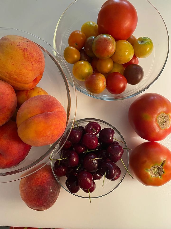 Cherries in a bowl, peaches in a bowl and tomatoes